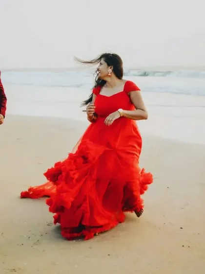 A playful and candid moment captured on the beach. The couple is running along the shore in their matching red outfits, creating a fun and natural pre-wedding photo.