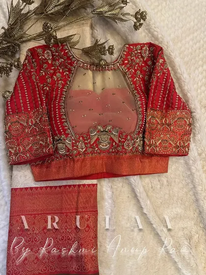 A stunning red bridal blouse with an illusion neckline. The sheer net panel is delicately embroidered, giving the impression that the work is directly on the skin.