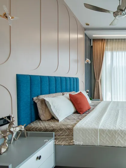A different angle of the bed, emphasizing the texture of the blue headboard and the gentle curves of the pastel pink wall paneling. The design creates a soft and inviting focal point in the room.