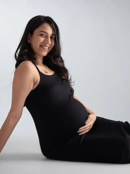 A relaxed, seated portrait of the mother-to-be. Her radiant smile and the simple black dress create a timeless and elegant look.