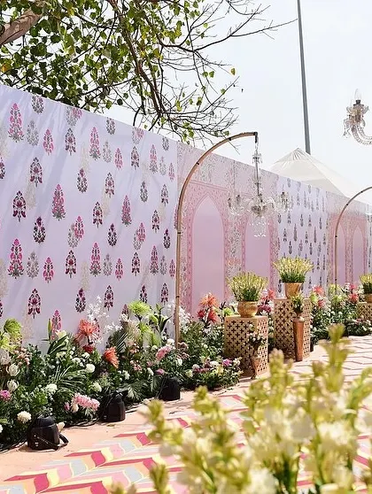 The entrance walkway, lined with florals and set against a backdrop of custom-printed fabric panels with traditional motifs.
