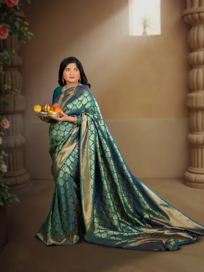 A timeless maternity portrait celebrating the grace of motherhood. This mother-to-be is captured in a classic studio setting, draped in an elegant teal and gold silk saree, creating a regal and artistic memory of her pregnancy.