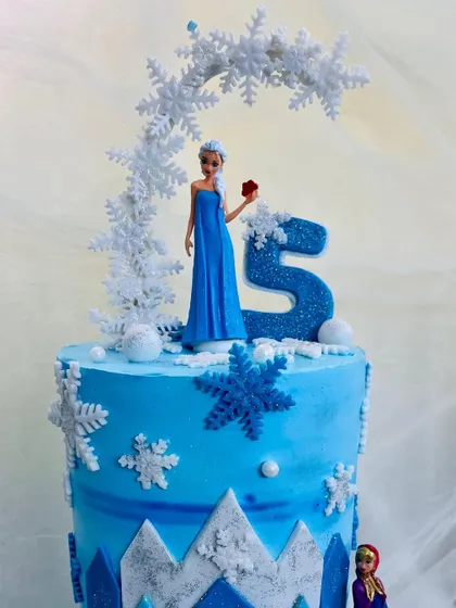 A close-up of my Elsa-themed cake, showing the detailed snowflake arch and the glitter on the number five. Every element is carefully crafted to capture the magic of the Frozen world.