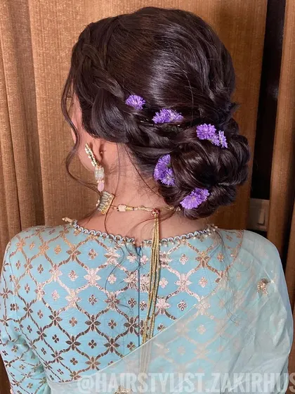 A side view of the updo, highlighting the loose tendrils and the delicate floral accents.