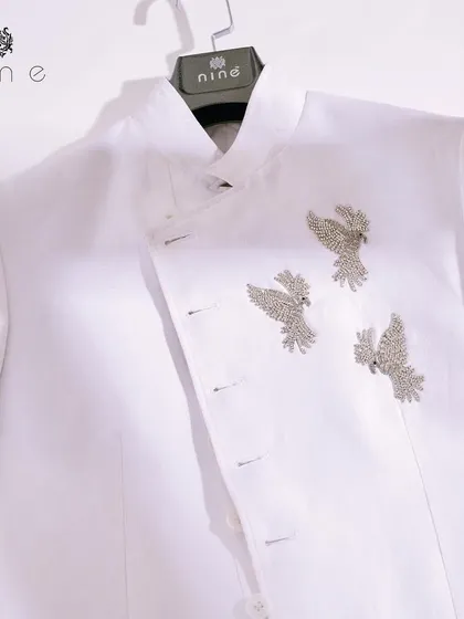 A clean, minimalist shot of our white angrakha-style jacket. The three silver-colored birds are the centerpiece, a statement of quiet confidence and exquisite taste.