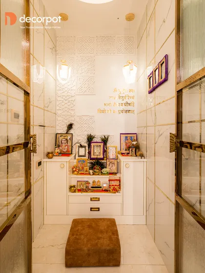 This dedicated pooja room uses white marble-finish tiles and fluted glass doors with brass frames to create a bright and opulent space. The custom storage unit provides ample space for pooja essentials.