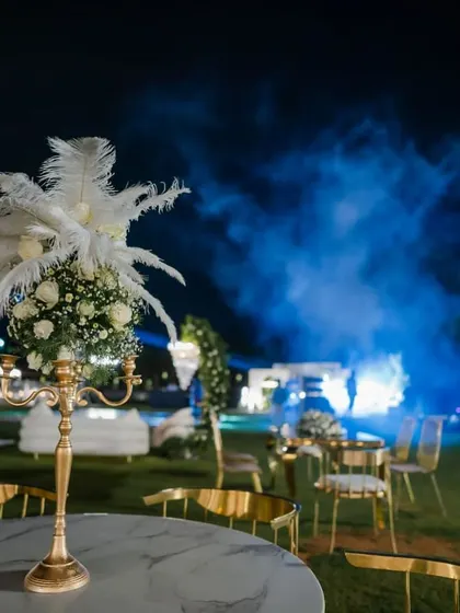 A close-up of a table centerpiece from an elegant 40th birthday party. I used a classic gold candelabra base and topped it with a delicate arrangement of white roses, baby's breath, and soft white feathers to add a touch of timeless charm and sophistication.