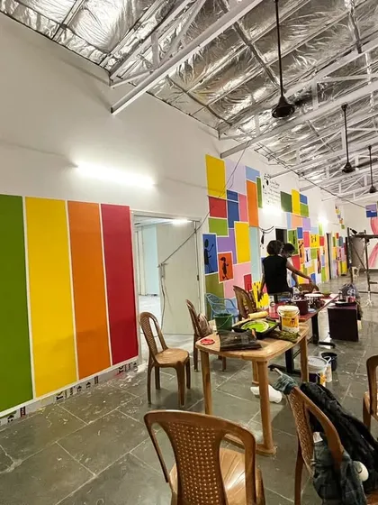 A wide shot of the Dharavi school project, showing the scaffolding and the sheer amount of color being added to the space.