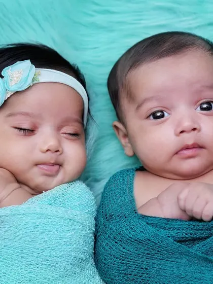 A beautiful portrait of newborn twins, one sleeping and one awake. This shot perfectly captures a real, unscripted moment between them.