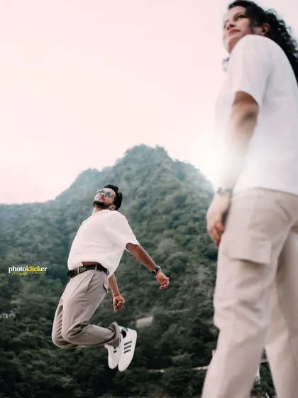 A fun, dynamic shot of the groom jumping in the air while his partner looks on, set against the mountains of Rishikesh.