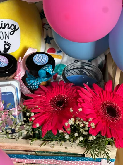 A close-up showing the fresh gerbera flowers and scented candles I added to this gender reveal hamper. These elements add a touch of elegance and sensory delight.