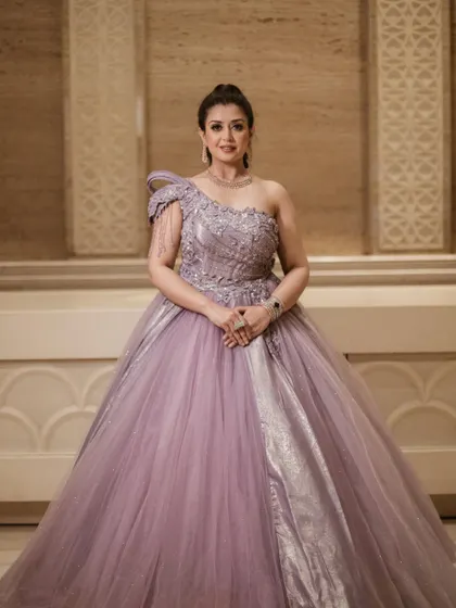 A classic portrait in our royal lavender ball gown. The model's pose showcases the gown's elegance and the intricate craftsmanship of the one-shoulder bodice.