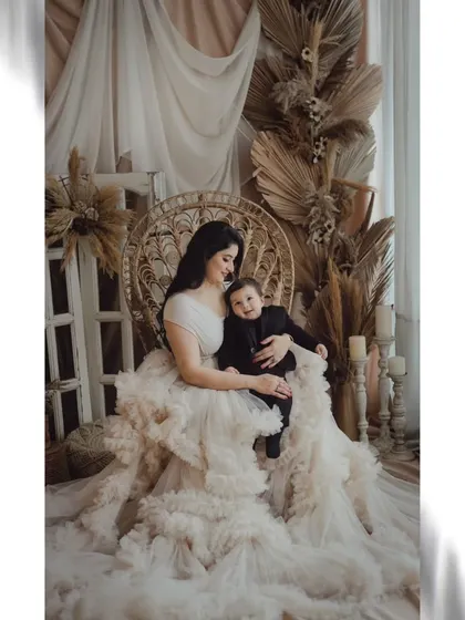 A mother's love in a dreamy setting. This portrait, with its soft lighting and elegant ruffled gown, captures the beautiful and serene side of motherhood.