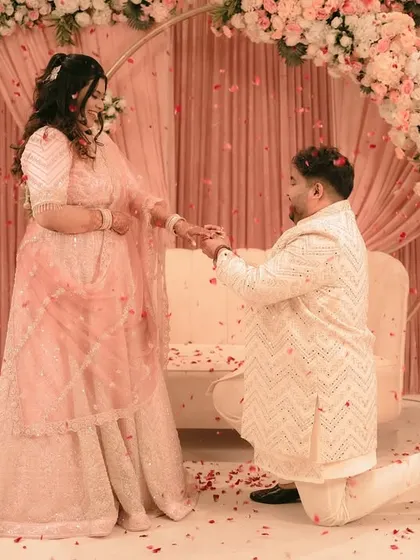 A romantic proposal during an engagement ceremony, with the groom on one knee under a shower of petals.