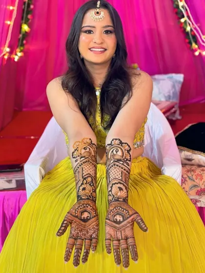 A smiling bride proudly displaying her intricate bridal henna.