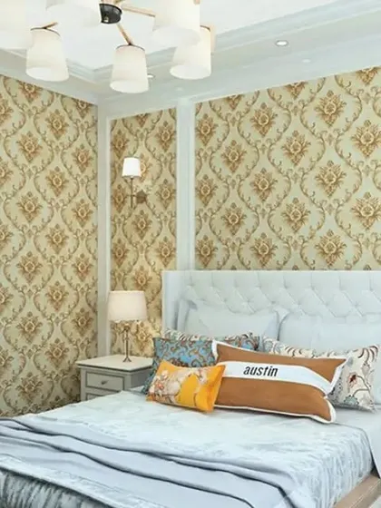 A bedroom featuring a classic gold and beige damask wallpaper, complemented by white furniture.
