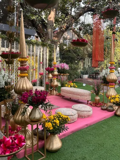 A side view of the pink and marigold mandap, showcasing the layers of floral decor and the beautiful natural light.