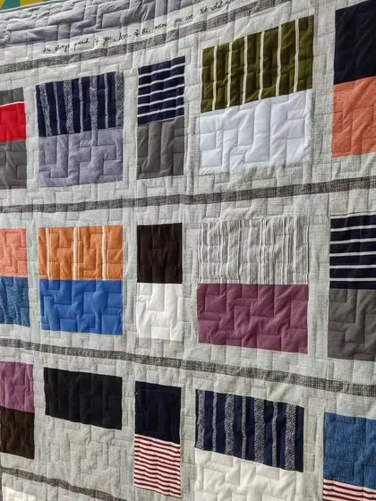 Detail of a memory quilt made from T-shirts, featuring handwritten messages embroidered onto the fabric.