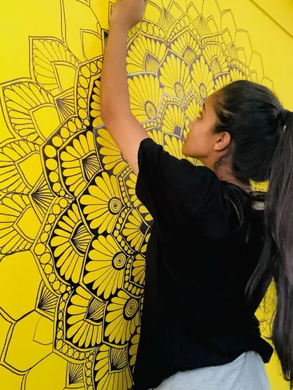 The more you use your creativity, the more you have. A shot of me reaching up to paint a large yellow mandala mural.