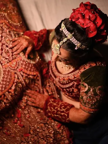 An artistic top-down shot of the bride admiring the intricate embroidery of her wedding lehenga.