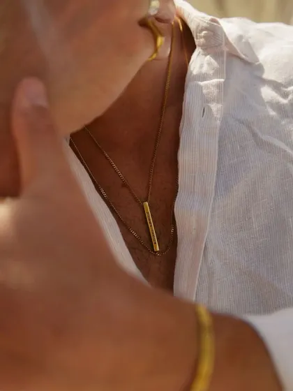 A candid shot of a man wearing a layered gold bar necklace. It shows how the piece integrates seamlessly into a relaxed, stylish look.