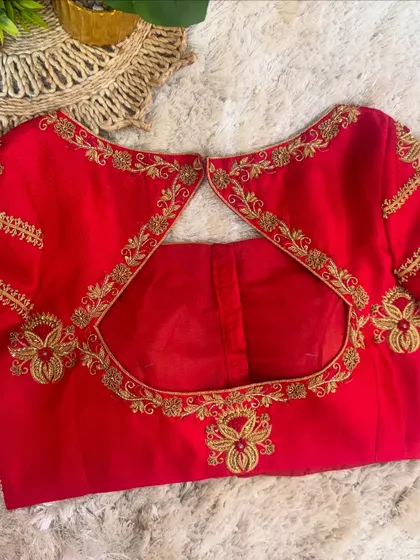 The back of the red blouse, showcasing a keyhole cut-out framed by intricate floral embroidery.
