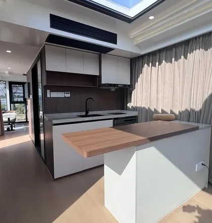 The kitchen in our Space Capsule model is compact but fully functional. It includes sleek cabinetry, a sink, and a countertop that doubles as a dining island, showcasing smart, space-saving design.