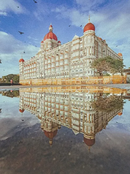 A stunning reflection of the Taj Mahal Palace hotel in a puddle, a different take on an iconic shot.
