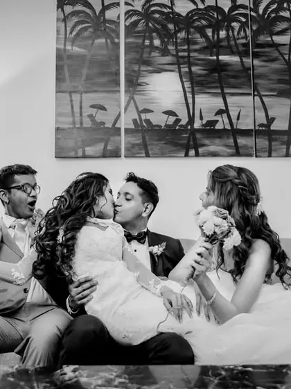 A fun and chaotic moment with the newlyweds and their friends. The couple's first kiss is surrounded by the laughter and cheers of their closest companions.