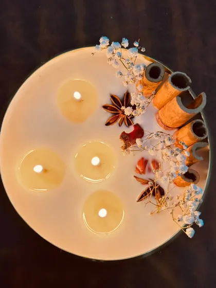 An overhead view of the lit 6-inch urli, showing the pool of melted wax and the beautifully arranged spices.