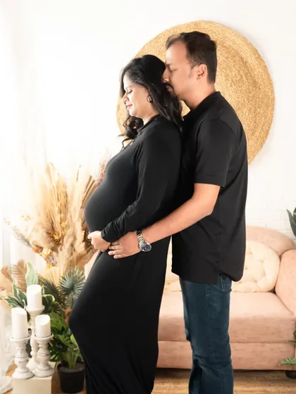 A serene and loving maternity portrait. The couple is dressed in simple black, creating a classic look that emphasizes their connection and the baby bump.
