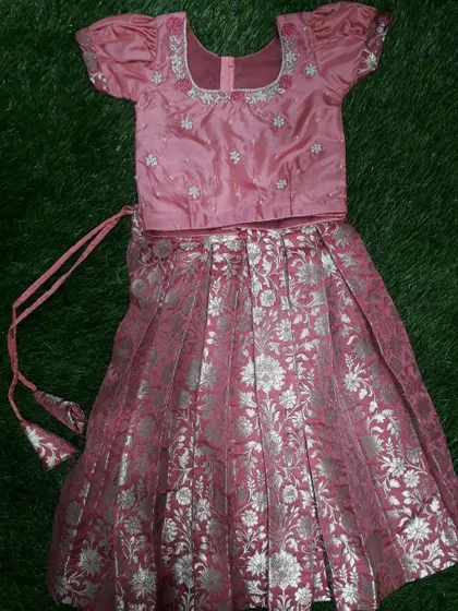 A traditional pink langa blouse for a one-year-old baby, made with brocade fabric and featuring silver handwork.