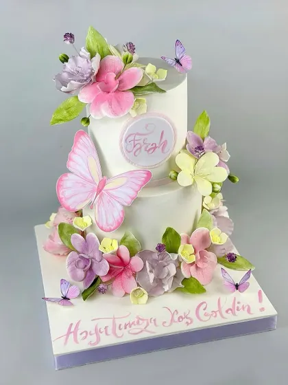 A magnificent two-tiered cake adorned with a cascade of pastel butterflies and flowers. This is a perfect centerpiece for a spring wedding or a dreamy birthday.