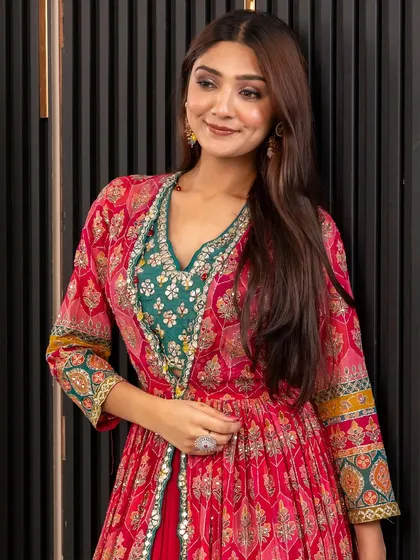 A close-up of this vibrant pink and green Indo-Western outfit. The printed jacket over a green crop top and red skirt is a celebration of color and style.