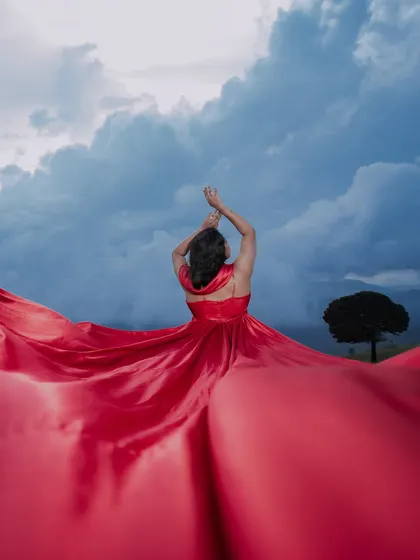 A dramatic solo portrait of the bride-to-be, with her vibrant red gown against a stormy sky. This shot showcases our artistic and creative approach to pre-wedding photography.