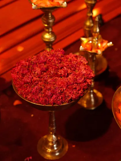 A close-up of the sacred items used in our 'Lal Bagh' temple-style wedding. Brass lamps and bowls of fresh red flowers were arranged to enhance the divine and traditional atmosphere.