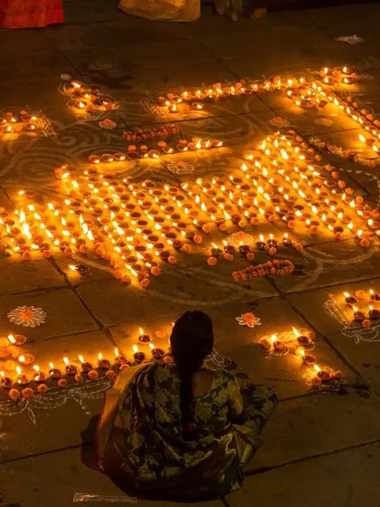 A beautiful rangoli made of hundreds of lit diyas on the ghats. This image showcases the artistic and community effort that goes into the festival.