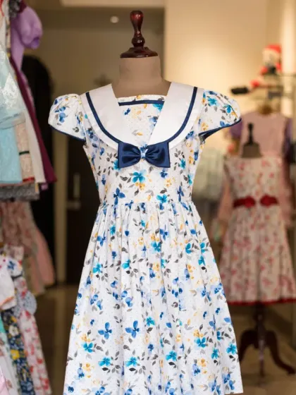 A classic sailor dress with a twist. This design features a beautiful blue floral print, a navy sailor collar, and a matching navy bow.