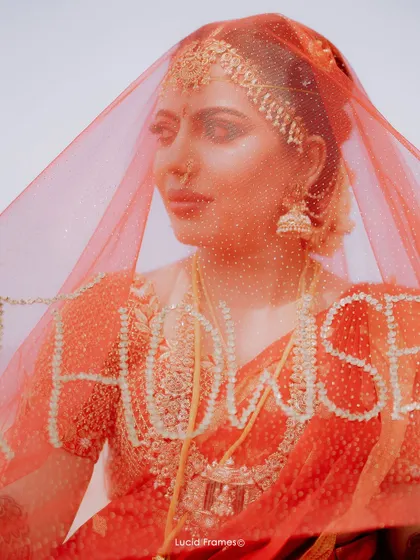 An artistic portrait of the bride through her red veil, which has custom embroidery.