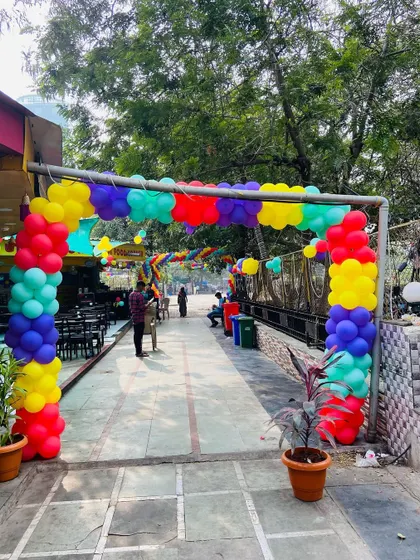 The entrance gate of an outdoor venue decorated with a colorful balloon arch.