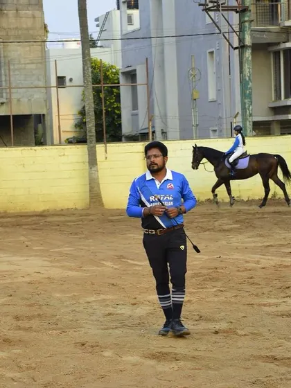 A trainer stands in the arena, whip in hand, ready for the next lesson. This image captures the discipline and focus that our coaching staff brings to every session.