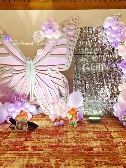 This fairy and butterfly photo booth combines a large 3D butterfly prop with a sparkling sequin wall, creating a glamorous and enchanting spot for pictures.