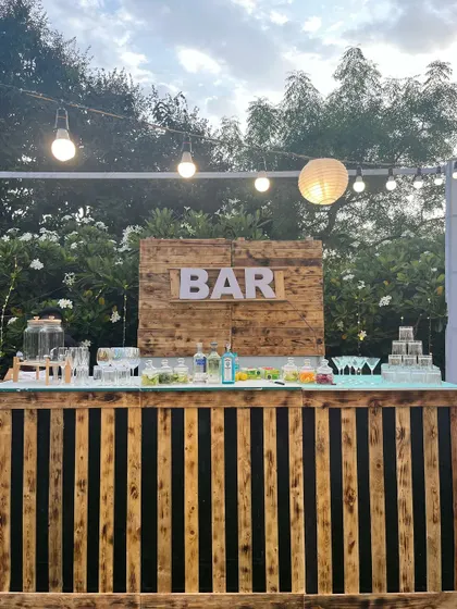 Our classic rustic bar, perfect for any daytime outdoor event. The counter is made of light and dark wooden slats, and the setup is completed with a wooden back panel featuring our "BAR" sign.