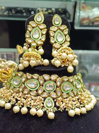 A heavy uncut Kundan choker set in a lovely pastel green shade. The matching jhumkas and pearl drops complete the look, making it an ideal choice for a bride or for attending a close family wedding.