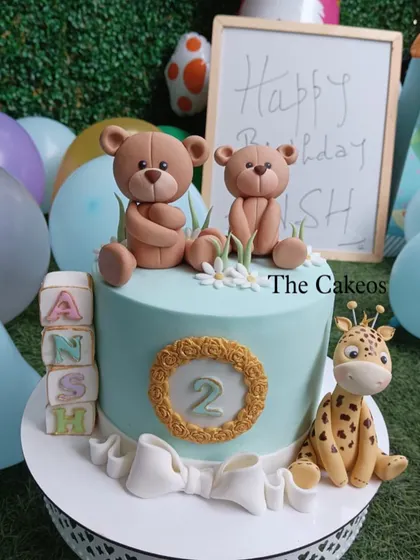 A lovely party scene featuring the teddy bear and giraffe cake, surrounded by balloons and a birthday sign.