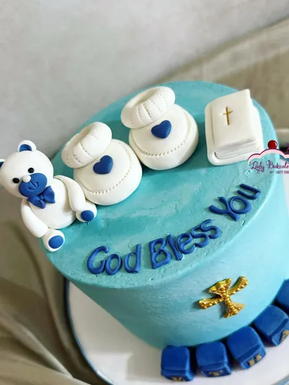A baptism cake for baby Ethan, in a lovely shade of blue. It's decorated with a teddy bear, baby booties, a bible, and personalized blocks.