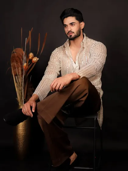 A classic seated pose that showcases the full ethnic outfit for men.