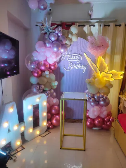 A whimsical and stylish 40th birthday setup featuring pastel and chrome balloons, a custom backdrop, marquee numbers, and a light-up butterfly accent.