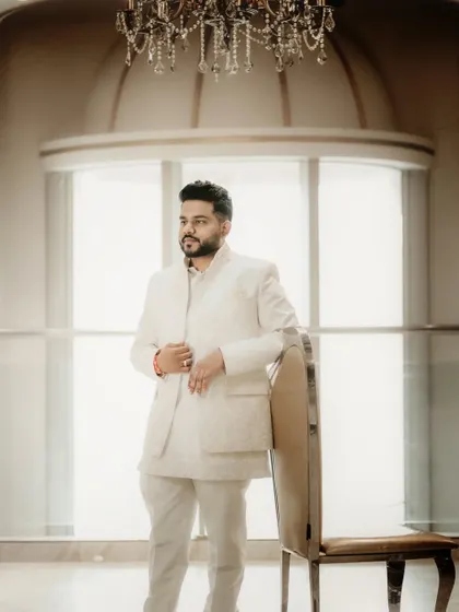A handsome groom-to-be posing in a classic white Jodhpuri suit before his engagement ceremony.