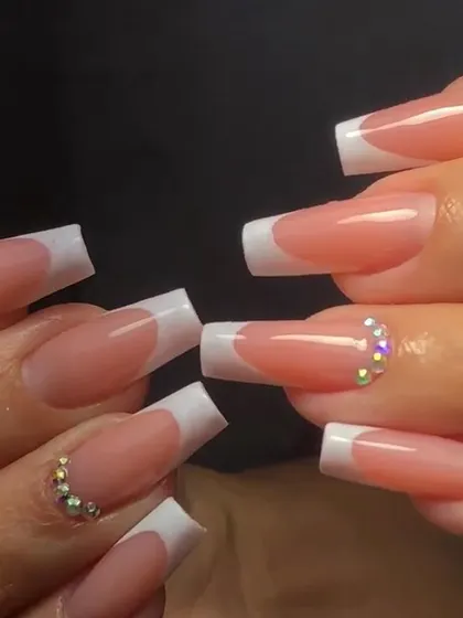 Long, square-tipped French nails with accent nails fully adorned with sparkling iridescent rhinestones for a glamorous effect.